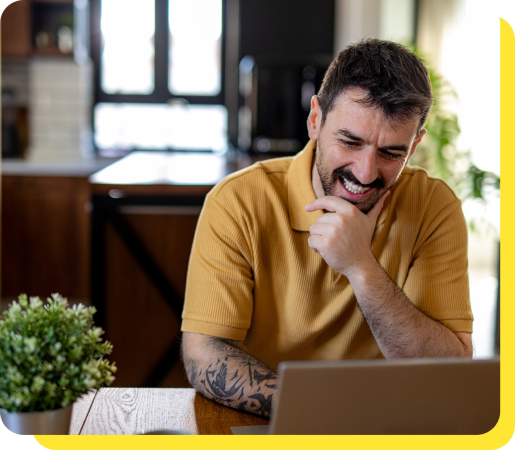 A man smiling while using a laptop, representing ease and convenience of applying for payroll loans online.