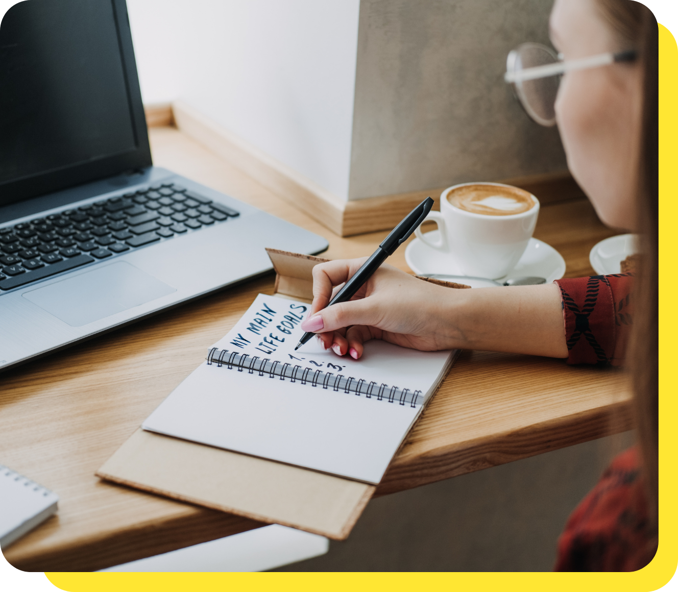 A person writing down savings goals before using a goal savings calculator