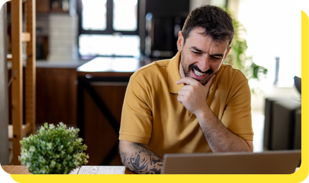 A man smiling while using a laptop, representing ease and convenience of applying for payroll loans online.