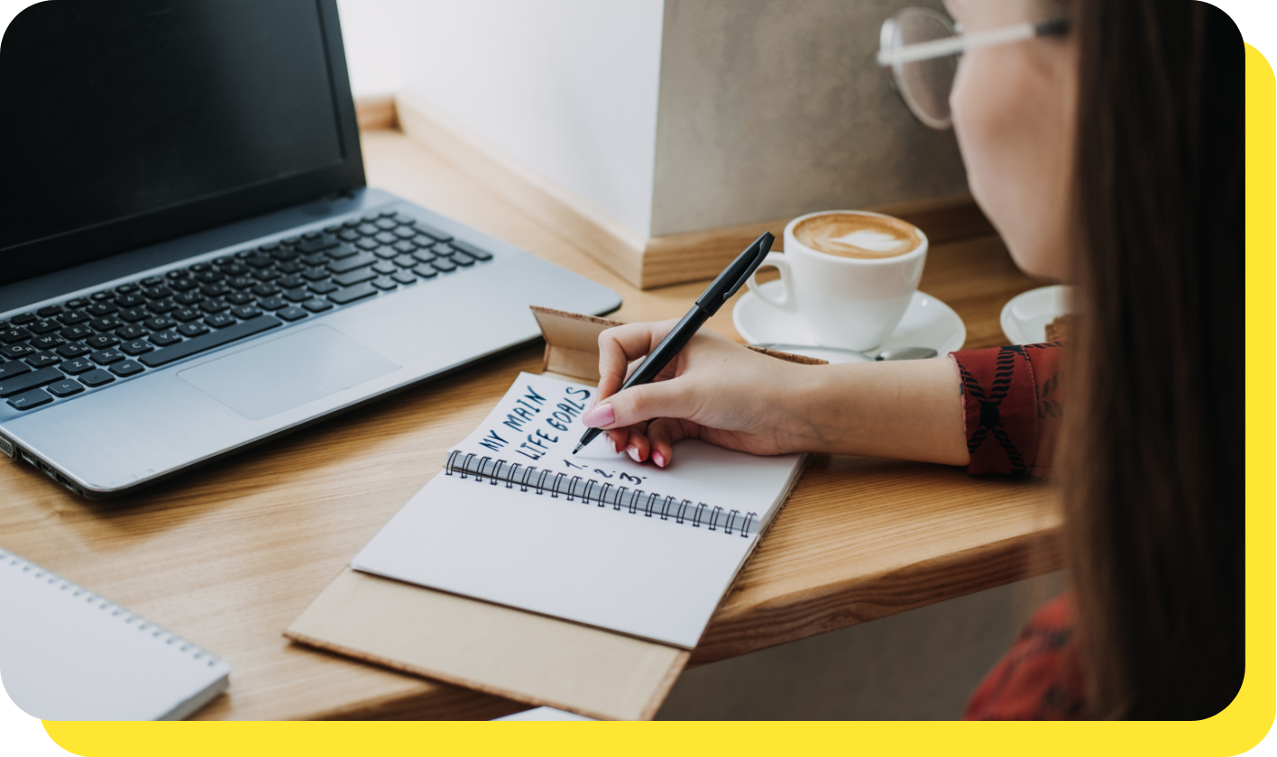 A person writing down savings goals before using a goal savings calculator