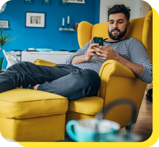 Man relaxing on a chair while using his phone, enjoying the stability of a fixed rate savings account.