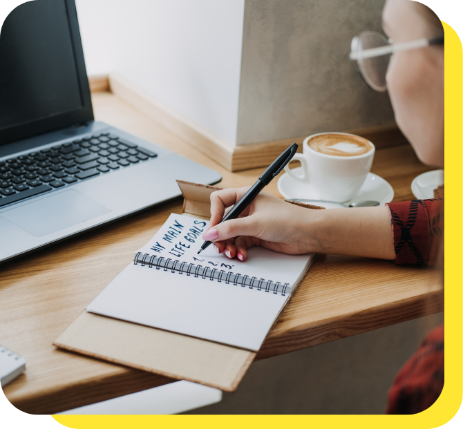 A person writing down savings goals before using a goal savings calculator
