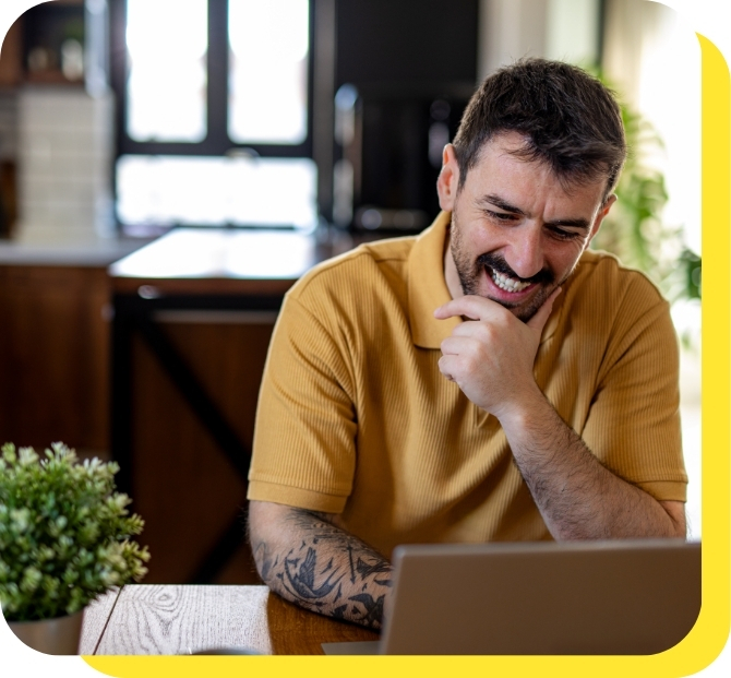 A man smiling while using a laptop, representing ease and convenience of applying for payroll loans online.