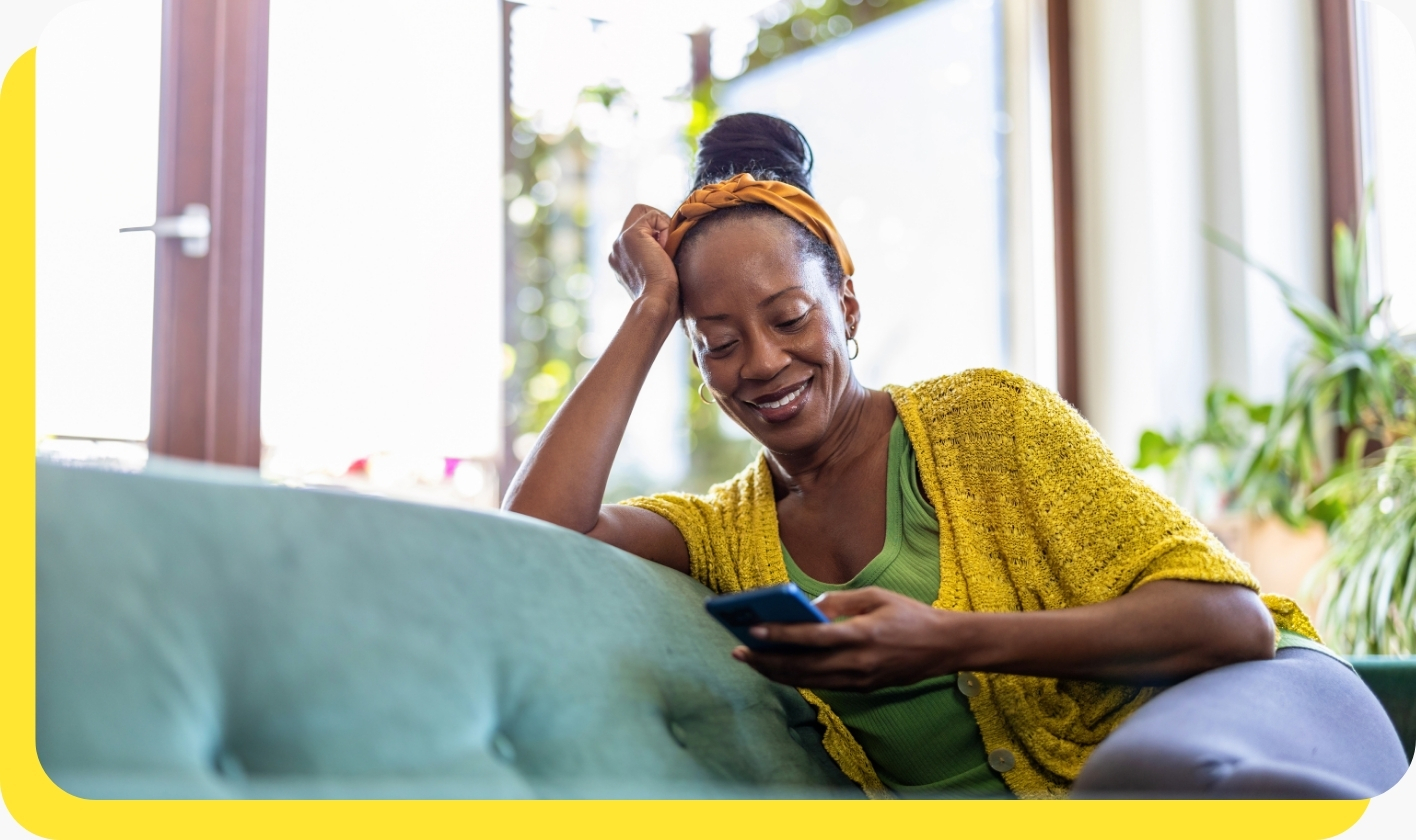 A woman smiling while looking at her phone, representing the ease and convenience of accessing payroll loans online.