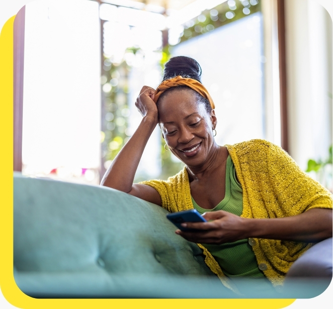 A woman smiling while looking at her phone, representing the ease and convenience of accessing payroll loans online.