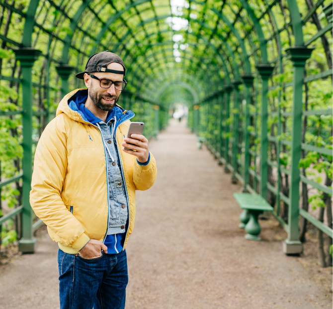 Man smiling while using his phone, managing his payroll savings with ease.