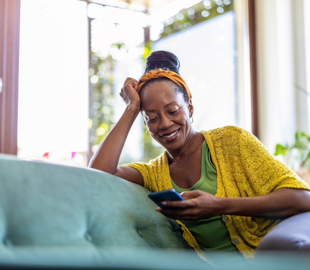 A woman smiling while looking at her phone, representing the ease and convenience of accessing payroll loans online.