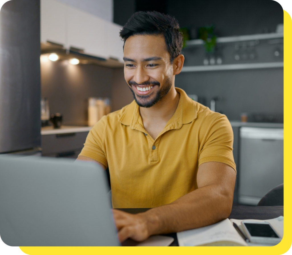 A man smiling while using his laptop to consolidate debt with a Serve and Protect debt consolidation loan, showcasing ease and financial relief.
