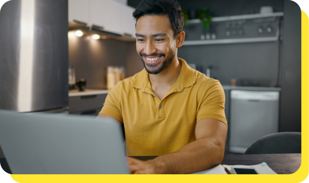 A man smiling while using his laptop to consolidate debt with a Serve and Protect debt consolidation loan, showcasing ease and financial relief.