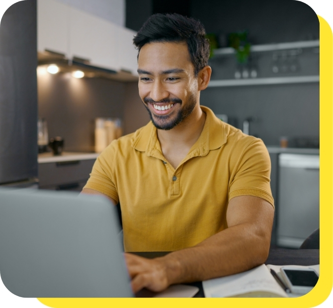 A man smiling while using his laptop to consolidate debt with a Serve and Protect debt consolidation loan, showcasing ease and financial relief.