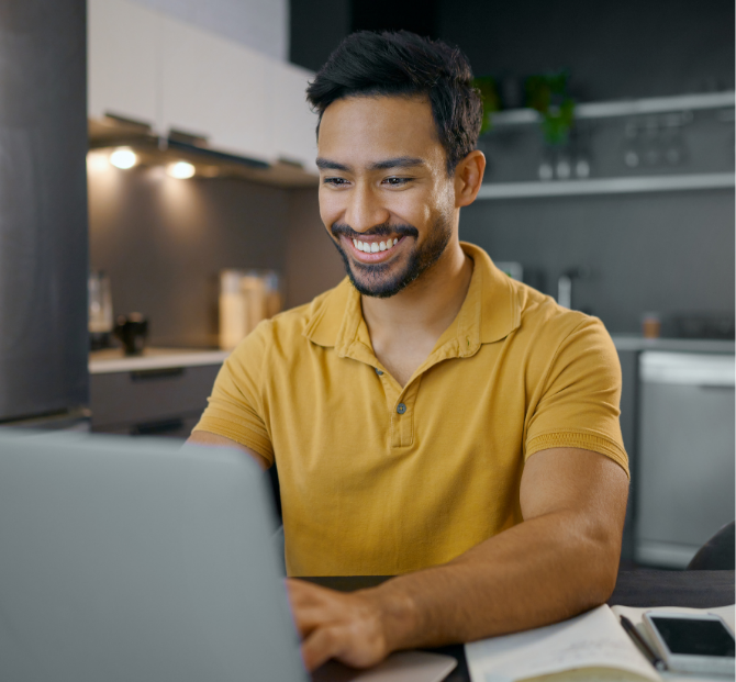 A man smiling while using his laptop to consolidate debt with a Serve and Protect debt consolidation loan, showcasing ease and financial relief.