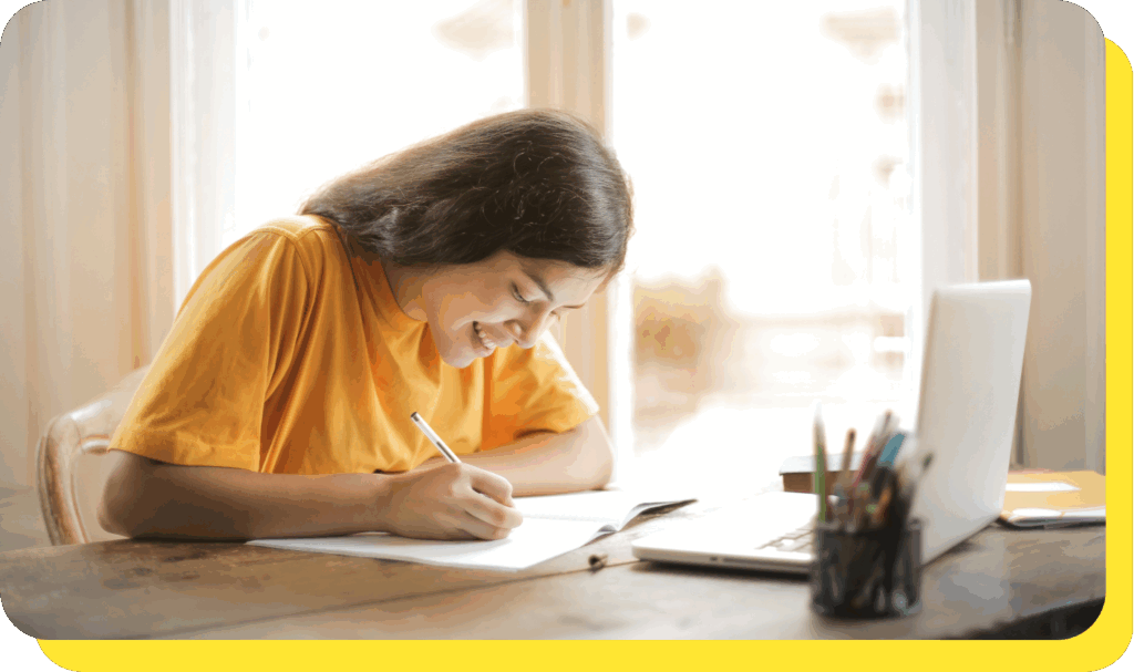 A woman sitting at a desk, smiling and focused while applying for a job on her laptop in a modern, professional workspace.