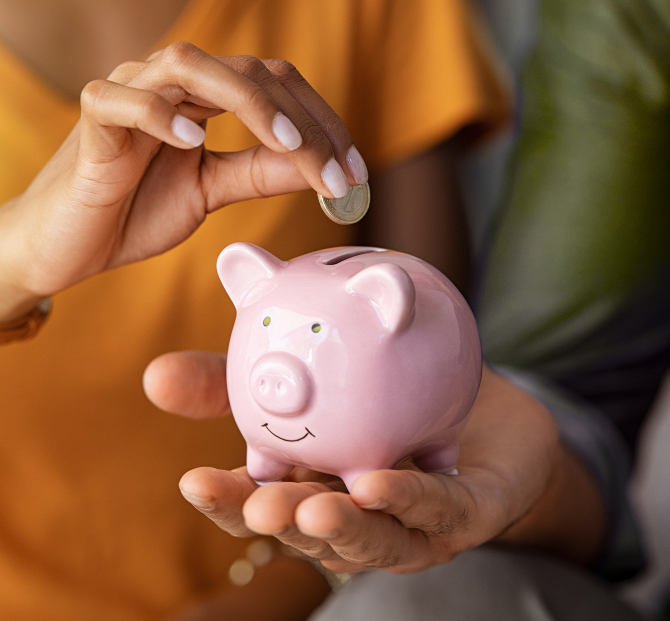 Hand placing coins into a piggy bank, representing saving and budgeting alongside a workplace loan.