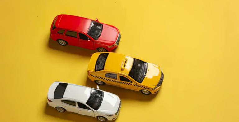 Three model cars -red, yellow taxi, and white - arranged on a bright yellow background, representing options for military car finance in the UK.