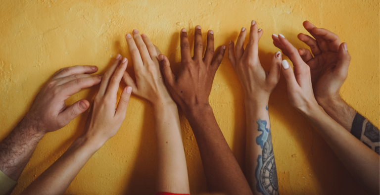 A group of hands raised together against a yellow background, representing cooperation and credit union benefits.